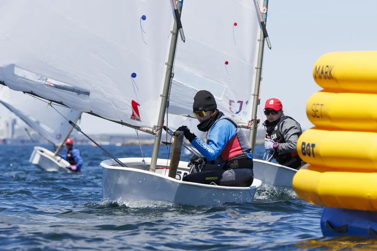 Navegante con gafas y gorro rodea una boya amarilla durante una regata.